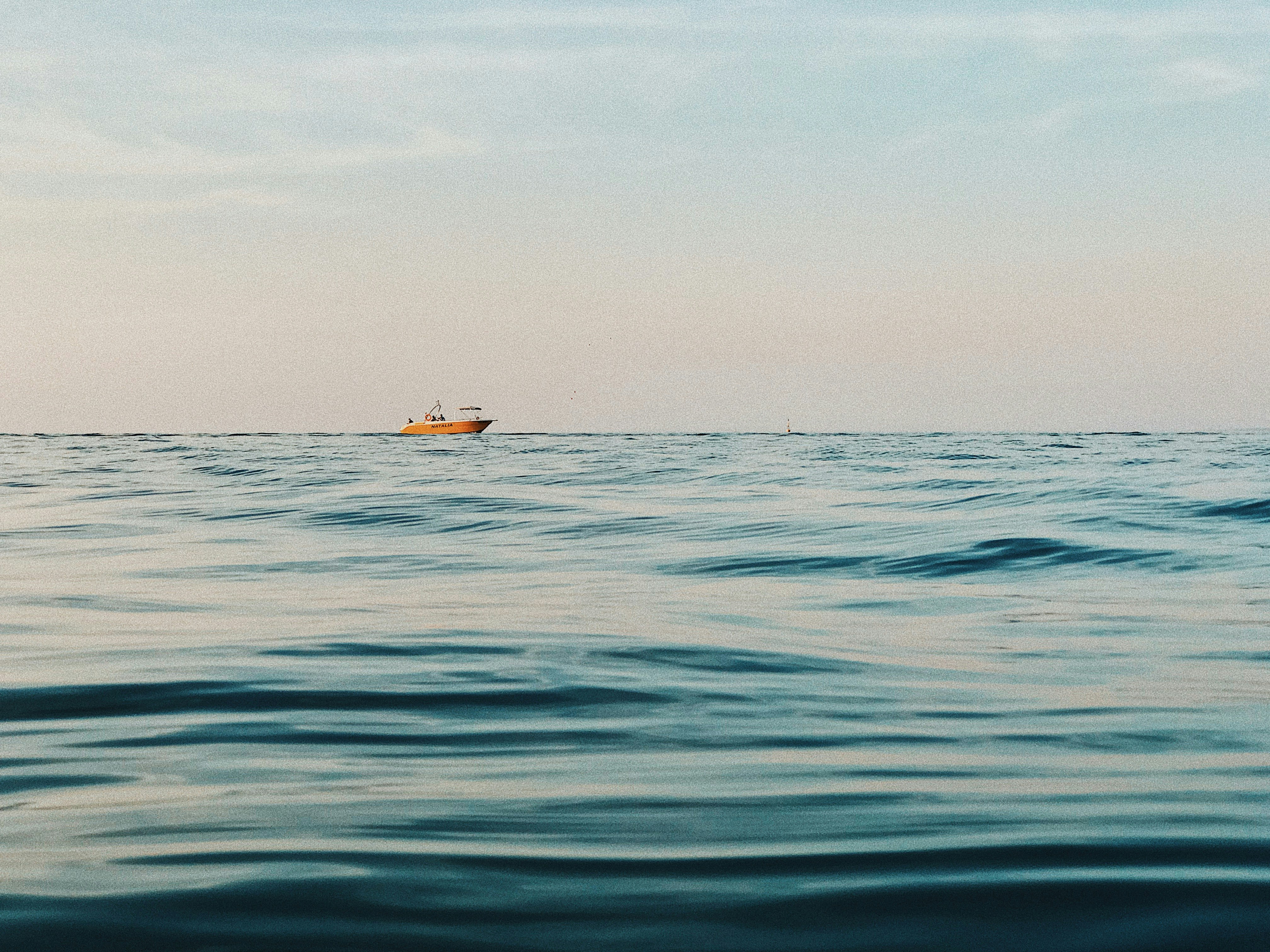 yellow and white boat on blue sea under white sky during daytime